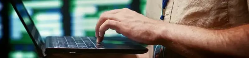 Fondo de un ingeniero trabajando en un laptop dentro de un centro de datos, tecnología y monitoreo de sistemas.