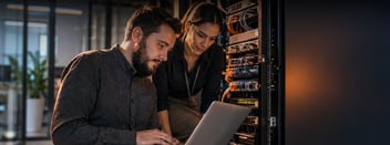 Ingenieros de TI realizando mantenimiento preventivo con laptop en rack de servidores
